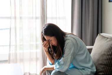 Yalnız genç bir kadın evde otururken depresyonda ve stresli hissediyor, negatif duygu ve zihinsel sağlık kavramı.