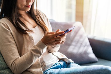 Genç bir kadın akıllı telefon kullanıyor ve sabahları evdeki kanepede dinleniyor.