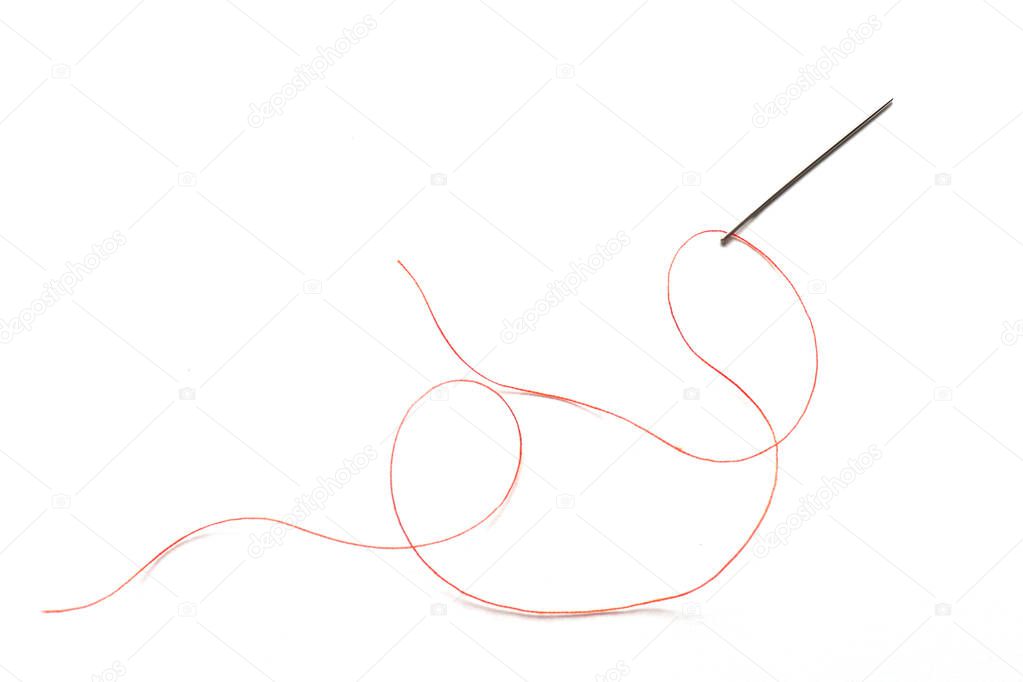 Needle with orange thread on a white background. Sewing accessories needle and thread