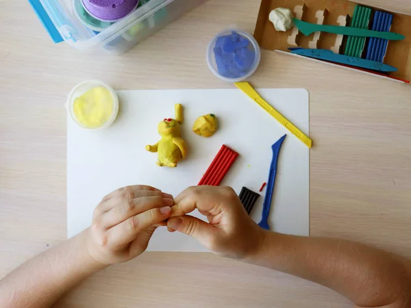 The child plays and sculpts figures from plasticine. Childrens hands with colored plasticine. Childrens games and creativity on vacation. Development of fine motor skills of fingers in children — Foto Stock