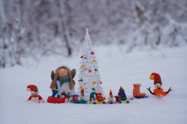 Plastikten yapılmış bir Noel treni ve karlı bir ormanda bir melek figürü..