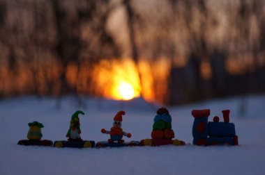 Günbatımının arka planında Noel oyuncakları olan oyuncak tren.