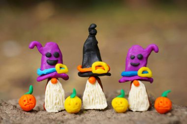 Şenlik şapkalı üç cüce figürü. Yakında balkabağı figürleri var..