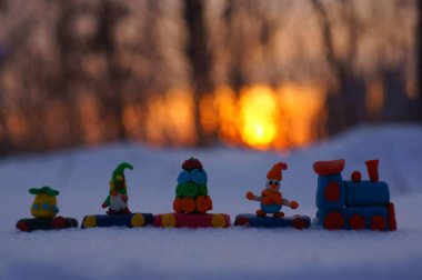 Günbatımının arka planında Noel oyuncakları olan oyuncak tren.