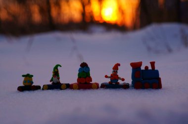 Günbatımının arka planında Noel oyuncakları olan oyuncak tren.