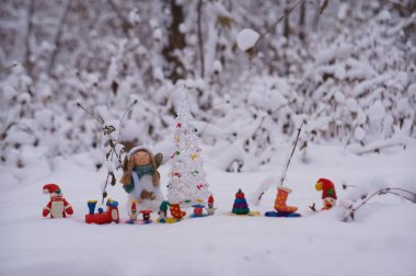 Plastikten yapılmış bir Noel treni ve karlı bir ormanda bir melek figürü..