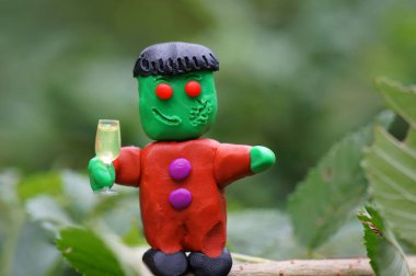 Bir bardak şampanyayla plastikten yapılmış komik bir canavar figürü. Cadılar Bayramı teması.