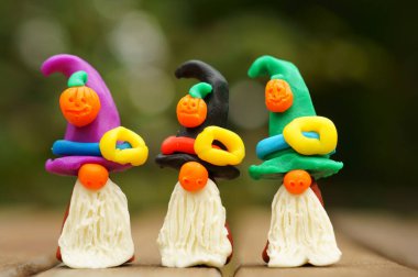 Bir şenlik şapkası ve balkabağıyla süslenmiş plastikten yapılmış üç cüce figürü. Cadılar Bayramı konsepti.