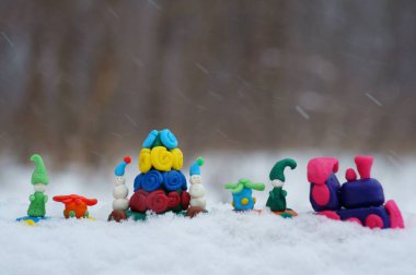 Kar yağışının arka planında Noel oyuncakları olan oyuncak tren..