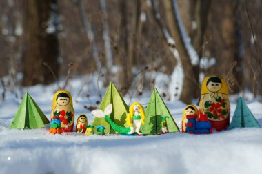 Karlı bir ormanda peri masalı karakterleri. Matrioshka, büyücü, deniz kızı, kağıt Noel ağacı ve cüce..