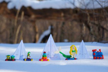 Karlı bir ormanda kağıt oyuncak Noel ağaçları. Yanındaki oyuncak tren plastikten yapılma..