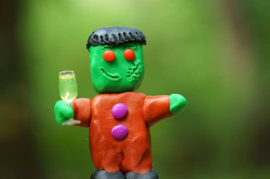 Bir bardak şampanyayla plastikten yapılmış komik bir canavar figürü. Cadılar Bayramı teması.