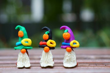 Bir şenlik şapkası ve balkabağıyla süslenmiş plastikten yapılmış üç cüce figürü. Cadılar Bayramı konsepti.