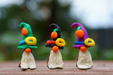 Bir şenlik şapkası ve balkabağıyla süslenmiş plastikten yapılmış üç cüce figürü. Cadılar Bayramı konsepti.