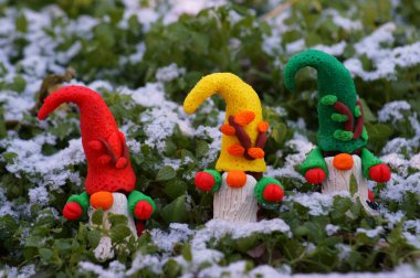 Karlı bir ormanda üç cücenin figürleri.