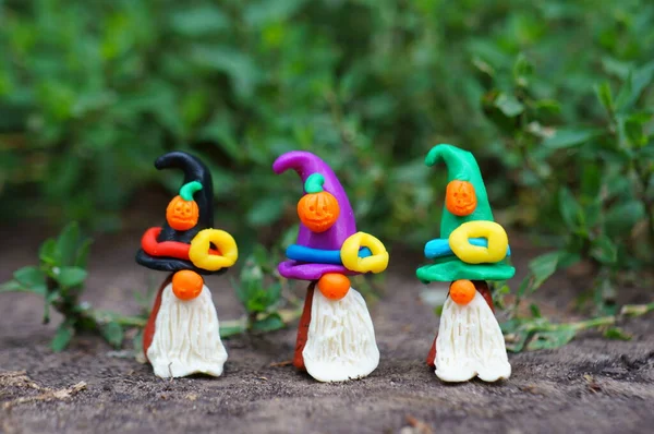 Bir şenlik şapkası ve balkabağıyla süslenmiş plastikten yapılmış üç cüce figürü. Cadılar Bayramı konsepti.