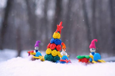Plastikten yapılmış bir kar aracındaki Noel figürleri Noel ağacı ve hediyeler taşıyor. Eylem, karlı bir ormanda gerçekleşiyor..