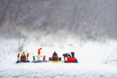 Karların arkasında Noel figürleri olan oyuncak tren..
