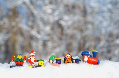 Kış ormanında peri masalı karakterleri ve hediyeleri olan oyuncak tren. Cüce, Noel Baba, penguen ve kardan adam.