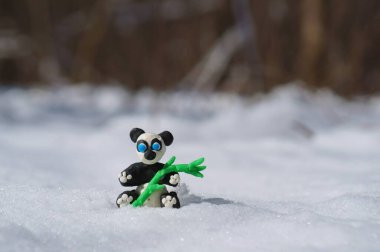 Karlı bir ormanda plastikten yapılmış panda heykelciği..