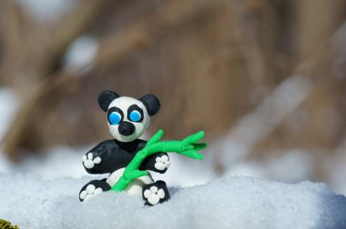 Karlı bir ormanda plastikten yapılmış panda heykelciği..