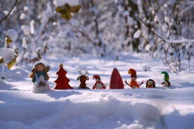 Kardan adam, Noel Baba, geyik, cüce, melek ve penguen heykelcikleri karlı ormanda. Muhteşem yeni yıl karakterleri.
