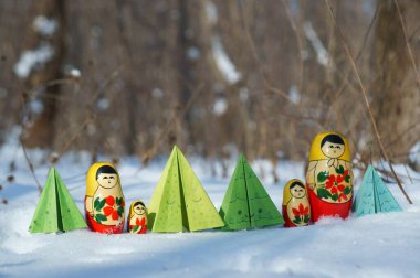 Karlı bir ormanda bir sıra yuva yapan bebek ve oyuncak Noel ağaçları..