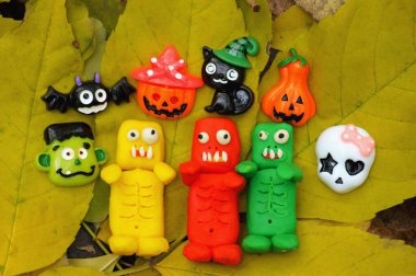 Sonbahar yaprağında üç komik renkli zombi. Cadılar Bayramı rakamlarının yanında..