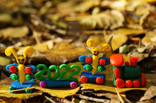A toy train with fairy-tale characters and the number 2022. Against the background of autumn leaves.