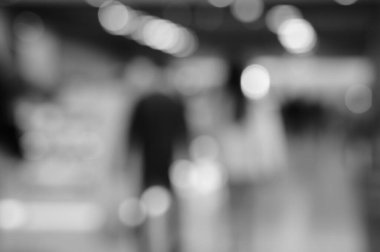 Arka plan bulanık. Alışveriş merkezindeki insanların siluetleri. Siyah beyaz fotoğraf.