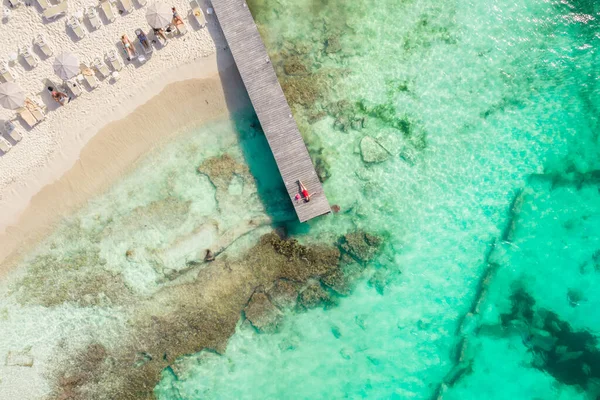 Luftaufnahme einer Frau, die an einem sonnigen Sommertag in Cancun, Mexiko, auf einem Holzsteg liegt, von oben. Junge sexy Frau im roten Badeanzug im Sommer in der Karibik. Sommerferienkonzept — Stockfoto