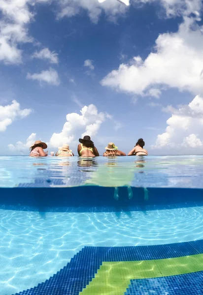 Half onderwater gespleten beeld van jonge vrouwen die plezier hebben in het zwembad van het hotel in Caribische zee. Begrip vakantie en vrijgezellenfeest — Stockfoto