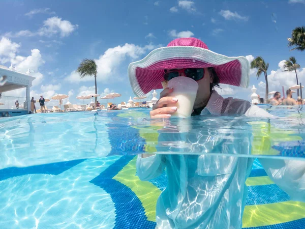 Mujer con sombrero en la piscina bebiendo cóctel. Concepto de unas felices vacaciones —  Fotos de Stock