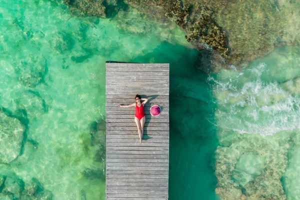 Draufsicht einer Frau, die sich an einem sonnigen Sommertag in Cancun, Mexiko, auf einen Holzpier legt. Junge sexy Frau in roter Badebekleidung auf Karibik. Sommerferienkonzept — Stockfoto