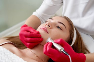 Kozmetik uzmanı bir hastanın yüzünü temizliyor. Cilt temizleme ve esnekliğin yenilenmesi kavramını benimse