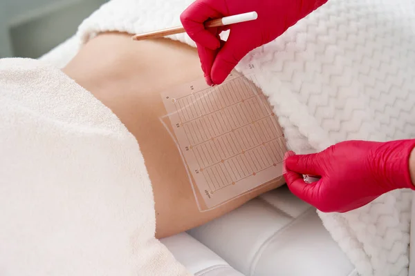 Young woman getting fat reductive skin lifting body treatment by a cosmetologist. Attractive female patient enjoying slimming body contouring procedure — Stock Photo, Image