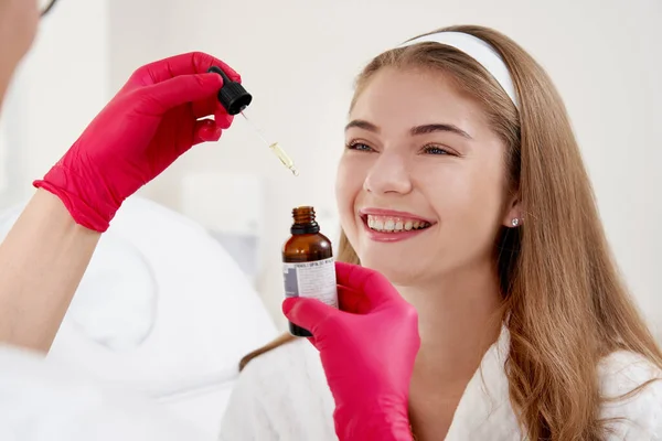 Face Skin Care. Closeup Of Beautiful Smiling Woman Receiving Serum Oil Treatment In Beauty Salon. Cosmetologist Applying Cosmetic Serum On female Face At Cosmetology Center — Stock Photo, Image