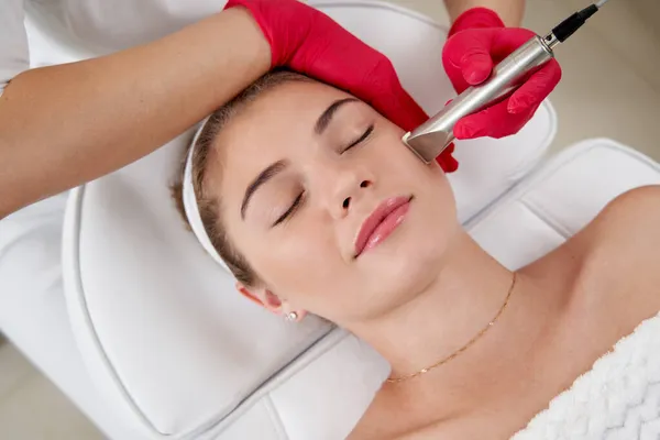 Cosmetologist making hardware cleaning of the face of beautiful young patient. Concept skin cleansing and restoration of elasticity — Stock Photo, Image