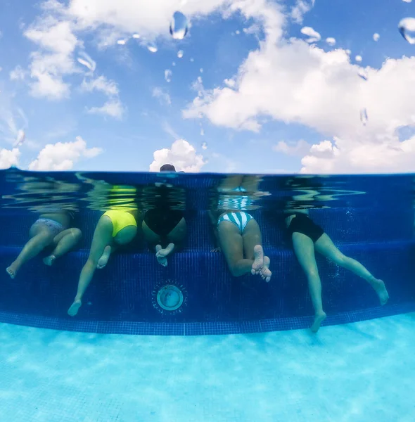 Half underwater split image of young women having fun in hotel pool in Caribbean sea. Concept of vacation and bachelorette pool party