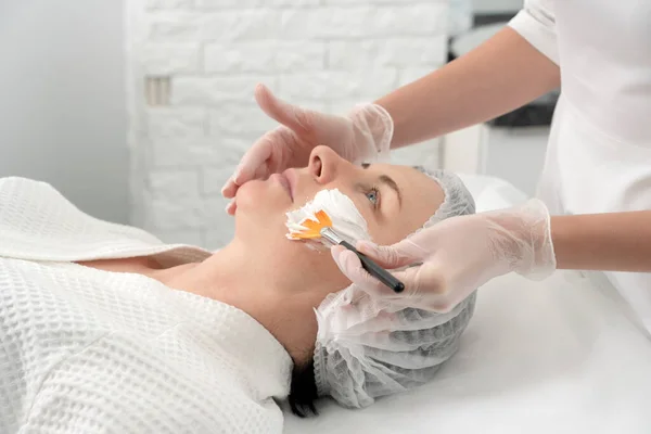 Mature woman receiving wwhte facial mask in spa beauty salon. Concept of skin care for older people — Stock Photo, Image