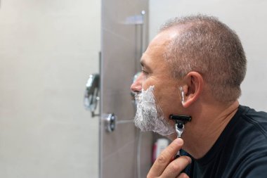 Yakışıklı, beyaz saçlı, sakalını tıraş eden, aynaya bakan bir adam. Biçim değiştirme kavramı