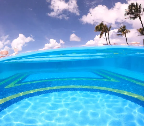 Split foto van een leeg zwembad en blauwe lucht met palmbomen — Stockfoto