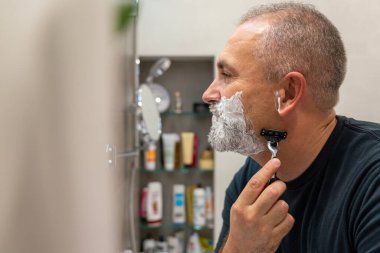 Yakışıklı, beyaz saçlı, sakalını tıraş eden, aynaya bakan bir adam. Biçim değiştirme kavramı