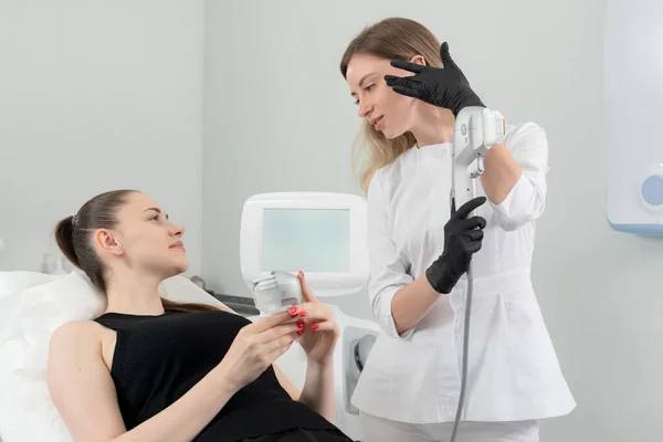 Ung kvinna som får laserbehandling på kosmetologiska kliniken Stockbild