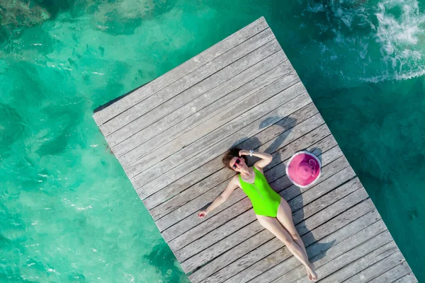 Luftaufnahme einer Frau, die an einem sonnigen Sommertag in Cancun, Mexiko, auf einem Holzsteg liegt, von oben. Junge sexy Frau in hellem Badeanzug im Sommer in der Karibik. Sommerferienkonzept — Stockfoto