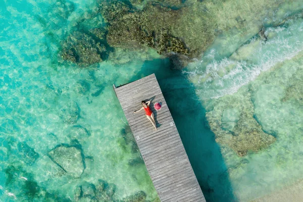 Luftaufnahme einer Frau, die an einem sonnigen Sommertag in Cancun, Mexiko, auf einem Holzsteg liegt, von oben. Junge sexy Frau in hellem Badeanzug im Sommer in der Karibik. Sommerferienkonzept — Stockfoto