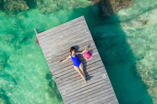 Vista aérea de la mujer tendida en el muelle de madera en el soleado día de verano en Cancún, México, vista superior. Mujer sexy joven con traje de baño brillante en verano en el Caribe. Verano playa vacaciones concepto —  Fotos de Stock