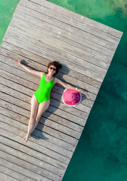 Widok z powietrza kobiety leżącej na drewnianym molo w słoneczny letni dzień w Cancun, Meksyk, widok z góry. Młoda seksowna kobieta w jasnych strojach kąpielowych w lecie na Karaibach. Letnia koncepcja wakacji na plaży — Zdjęcie stockowe