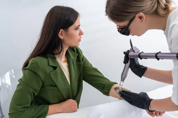 Cosmetólogo eliminación de tatuaje con dispositivo láser mano femenina. Concepto de borrar tatuajes como un procedimiento costoso en la clínica de cosmetología — Foto de Stock