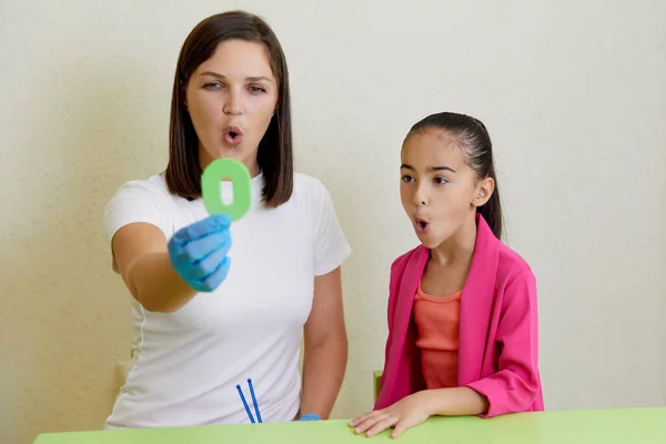 Speech therapist working with girl training pronunciation